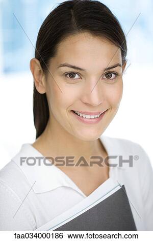 Young woman holding folder, smiling, portrait View Large Photo Image Stock Photograph - Young woman holding folder, smiling, portrait. Fotosearch