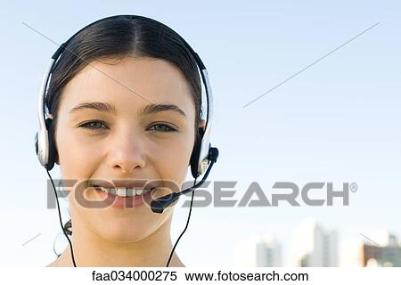 Young woman wearing headset, smiling at camera View Large Photo Image Stock Photography - Young woman wearing headset, smiling at camera. Fotosearch