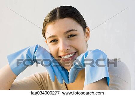 Young woman wearing rubber gloves, smiling at camera, hands under chin View Large Photo Image Stock Photo - Young woman wearing rubber gloves, smiling at camera, hands under chin. Fotosearch