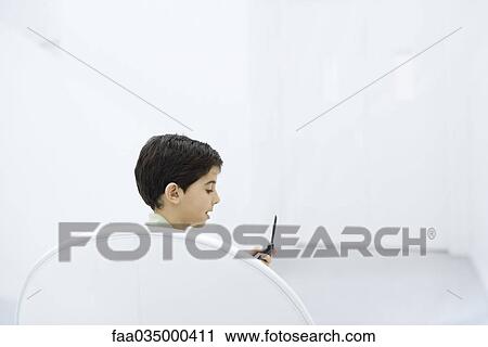 Boy holding cell phone, side view View Large Photo Image Stock Image - Boy holding cell phone, side view. Fotosearch
