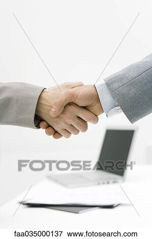 Stock Photo - Business associates shaking hands, cropped view. Fotosearch