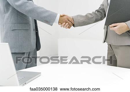 Stock Photo - Business associates shaking hands, cropped view. Fotosearch