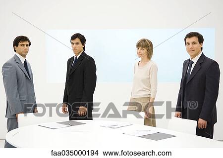 Picture - Business associates standing around conference table, looking at camera. Fotosearch