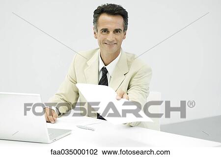 Businessman holding out document, smiling at camera View Large Photo Image Stock Image - Businessman holding out document, smiling at camera. Fotosearch
