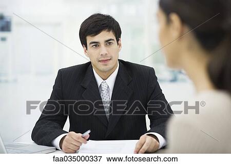 Businessman sitting at desk, listening to female client View Large Photo Image Stock Photo - Businessman sitting at desk, listening to female client. Fotosearch