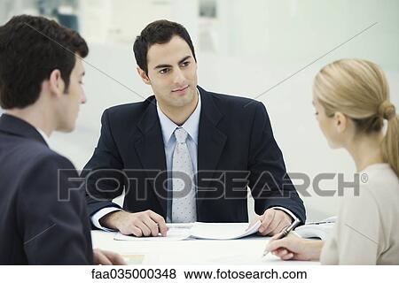 Businessman sitting with couple, woman signing document View Large Photo Image Stock Photo - Businessman sitting with couple, woman signing document. Fotosearch