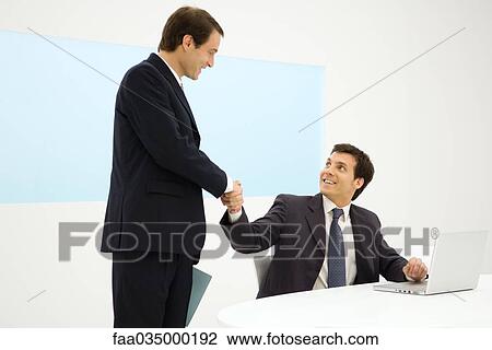 Businessmen shaking hands, smiling at each other View Large Photo Image Stock Image - Businessmen shaking hands, smiling at each other. Fotosearch