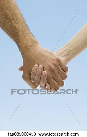 Couple holding hands, cropped view View Large Photo Image Stock Photo - Couple holding hands, cropped view. Fotosearch