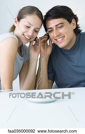 Couple sharing earphones, listening to portable CD player View Large Photo Image Stock Image - Couple sharing earphones, listening to portable CD player. Fotosearch