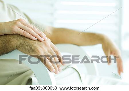 Couple sitting together, holding hands, cropped view View Large Photo Image Stock Image - Couple sitting together, holding hands, cropped view. Fotosearch