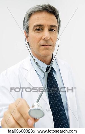 Stock Photography - Doctor holding stethoscope toward camera, focus on background. Fotosearch