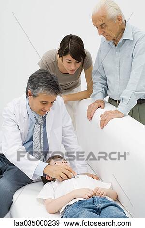 Stock Photo - Doctor listening to young patient's heart, family watching. Fotosearch