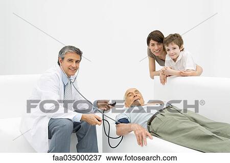 Doctor measuring elderly man's blood pressure, family leaning on couch, all smiling at camera View Large Photo Image Stock Photo - Doctor measuring elderly man's blood pressure, family leaning on couch, all smiling at camera. Fotosearch