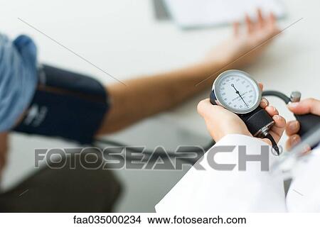 Picture - Doctor measuring patient's blood pressure, cropped view. Fotosearch