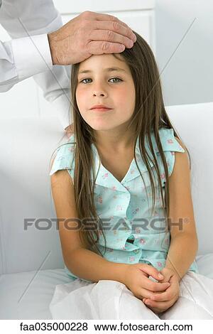 Stock Photo - Doctor placing his hand on little girl's forehead, cropped view. Fotosearch