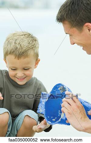 Stock Image - Father and son making sand castle, close-up. Fotosearch