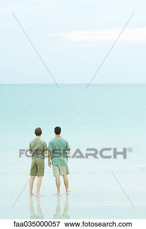 Father and son standing together on beach, looking at horizon View Large Photo Image Stock Photo - Father and son standing together on beach, looking at horizon. Fotosearch