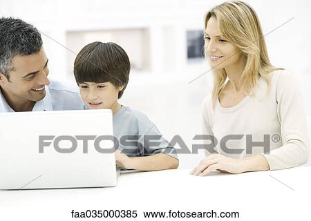 Father and son using laptop computer together, mother watching View Large Photo Image Stock Photography - Father and son using laptop computer together, mother watching. Fotosearch