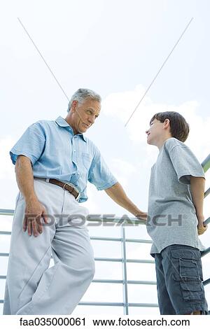 Grandfather and grandson standing by railing, looking at each other, low angle view View Large Photo Image Stock Image - Grandfather and grandson standing by railing, looking at each other, low angle view. Fotosearch