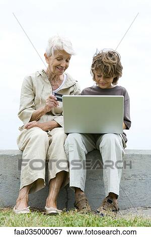 Grandmother and grandson using laptop outdoors, shopping online View Large Photo Image Stock Photo - Grandmother and grandson using laptop outdoors, shopping online. Fotosearch