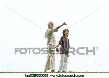 Stock Photography - Grandmother walking hand in hand with grandson, pointing to the distance. Fotosearch