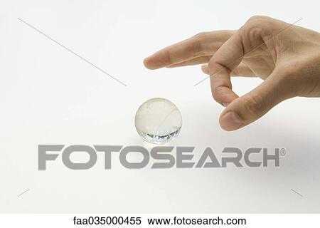 Hand about to flick small glass globe View Large Photo Image Stock Photography - Hand about to flick small glass globe. Fotosearch