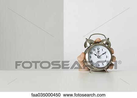 Stock Image - Hand holding alarm clock. Fotosearch