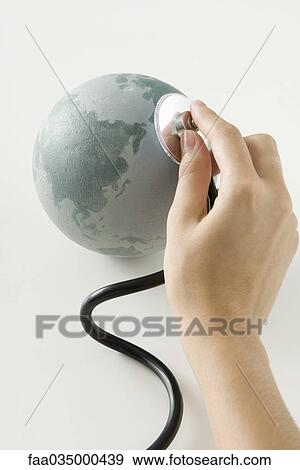 Hand holding stethoscope on small globe View Large Photo Image Stock Photo - Hand holding stethoscope on small globe. Fotosearch