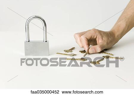 Hand selecting key for large padlock View Large Photo Image Stock Image - Hand selecting key for large padlock. Fotosearch
