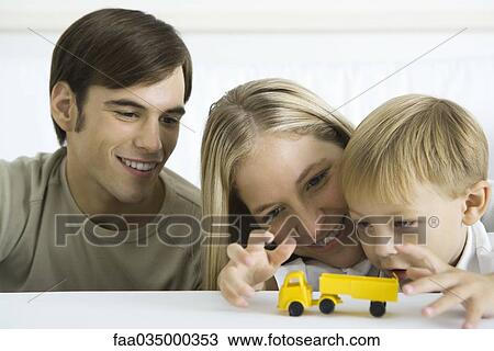 Little boy playing with toy truck, parents watching smiling View Large Photo Image Stock Image - Little boy playing with toy truck, parents watching smiling. Fotosearch