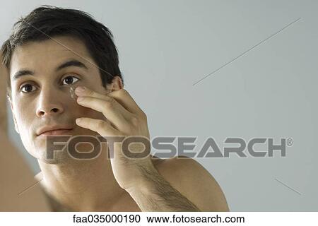 Man looking at himself in mirror, moisturizing face View Large Photo Image Stock Image - Man looking at himself in mirror, moisturizing face. Fotosearch