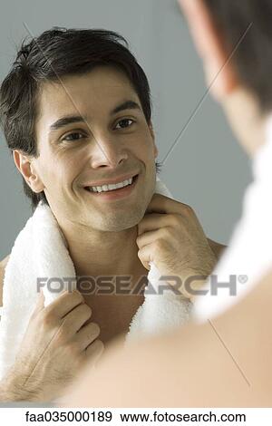 Man looking at self in mirror, smiling, holding towel on his shoulders View Large Photo Image Stock Photo - Man looking at self in mirror, smiling, holding towel on his shoulders. Fotosearch