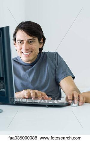 Man using desktop computer, smiling View Large Photo Image Stock Photo - Man using desktop computer, smiling. Fotosearch