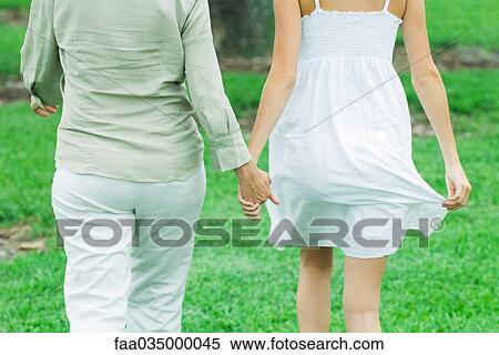 Mother and daughter walking outdoors, holding hands, cropped rear view View Large Photo Image Stock Photography - Mother and daughter walking outdoors, holding hands, cropped rear view. Fotosearch