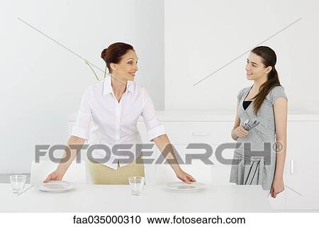 Mother and teen daughter setting the table together, smiling at each other View Large Photo Image Stock Image - Mother and teen daughter setting the table together, smiling at each other. Fotosearch