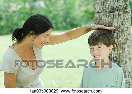 Mother measuring son's height on tree trunk View Large Photo Image Stock Photo - Mother measuring son's height on tree trunk. Fotosearch