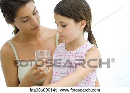 Stock Photography - Mother offering glass of water to daughter. Fotosearch