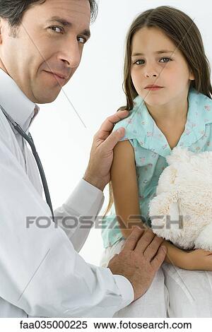 Stock Photography - Pediatrician comforting little girl, smiling over shoulder at camera. Fotosearch