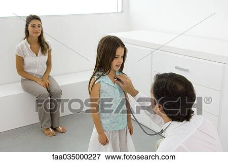 Pediatrician holding stethoscope to girl's chest, mother sitting nearby View Large Photo Image Stock Photo - Pediatrician holding stethoscope to girl's chest, mother sitting nearby. Fotosearch