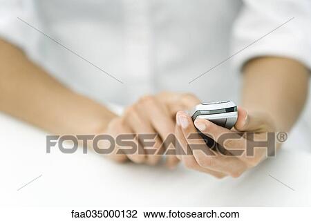 Stock Image - Person holding cell phone, cropped view. Fotosearch