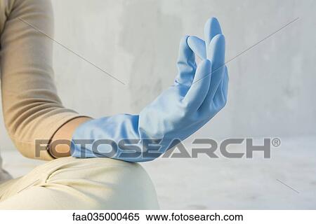 Stock Photography - Person meditating with hand in mudra position, wearing rubber glove, cropped view. Fotosearch