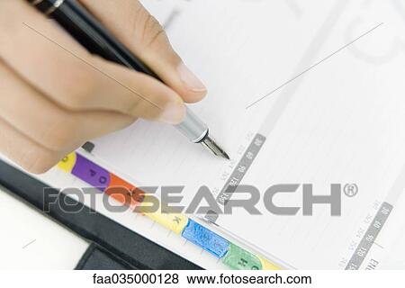 Stock Photo - Person writing in agenda, cropped view of hand. Fotosearch