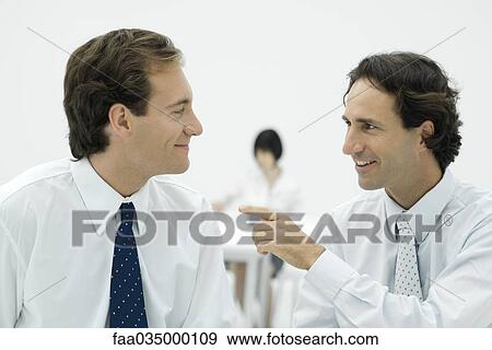 Professional men smiling at each other, one man pointing View Large Photo Image Stock Photo - Professional men smiling at each other, one man pointing. Fotosearch