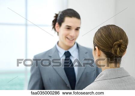 Professional young man facing female colleague, smiling View Large Photo Image Stock Photograph - Professional young man facing female colleague, smiling. Fotosearch