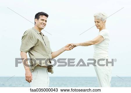 Stock Image - Senior woman and adult son face to face, holding hands. Fotosearch