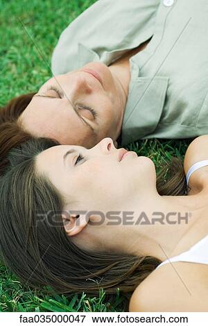 Teen girl and mother lying together on grass, high angle view View Large Photo Image Stock Photo - Teen girl and mother lying together on grass, high angle view. Fotosearch