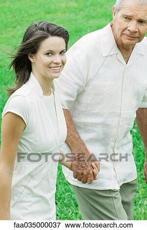 Teen girl walking hand in hand with grandfather, smiling at camera View Large Photo Image Stock Photo - Teen girl walking hand in hand with grandfather, smiling at camera. Fotosearch