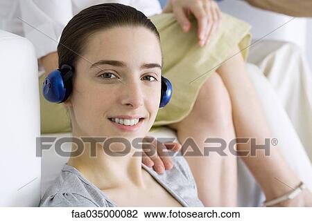Teenage girl listening to headphones, smiling at camera, woman's hand on her shoulder View Large Photo Image Stock Image - Teenage girl listening to headphones, smiling at camera, woman's hand on her shoulder. Fotosearch