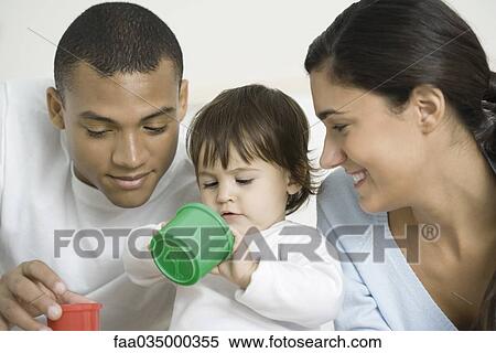 Toddler girl sitting between parents, playing with plastic toys View Large Photo Image Stock Photography - Toddler girl sitting between parents, playing with plastic toys. Fotosearch