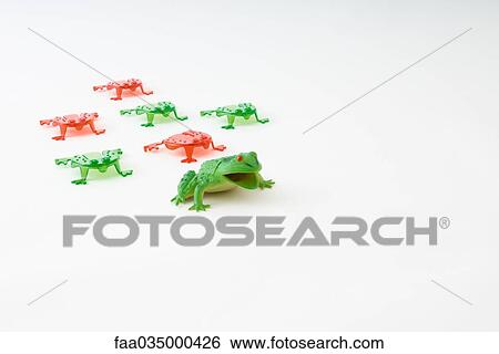 Stock Photograph - Toy frog leading group of smaller plastic frogs. Fotosearch